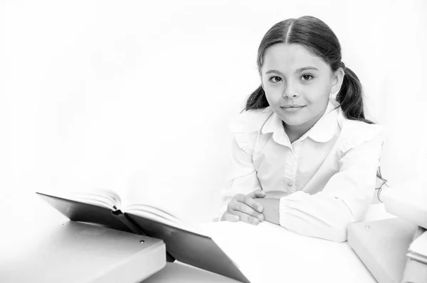 Девочка читала книгу сидя стол белый интерьер. Школьница изучает учебник. Детская школьная форма счастливое лицо читать книги. Возбужден знаниями. Концепция домашнего обучения. Интересная книга для детей — стоковое фото