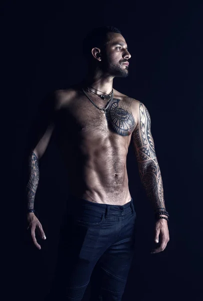 Cuidado del cuerpo con fitness y deporte. El hombre tatuado muestra un sexy torso muscular. Deportista con seis paquetes y ab. Culturista con bíceps y tríceps. Modelo de moda con tatuaje en jeans — Foto de Stock