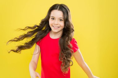 Moda güzeli. hippi çocuk. çocukluk mutluluğu. Uzun kıvırcık saçlı mutlu kız. Kuaför salonu. Cilt bakımı ve doğal saç. Küçük kız gülümsüyor. Rüzgarlı saçlar. Küçük manken. saç modası