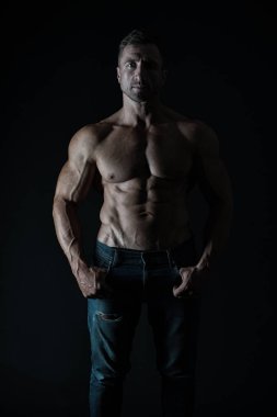 O doğuştan bir atlet. Siyah arka planda seksi atlet. Yakışıklı adam kas altı paketi abs gösteren. Atlet veya uygun güçlü gövde li atletik adam kot giyiyor