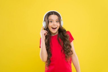 Teknoloji işe yaradığı zaman harikadır. Mutlu küçük kız sarı arka planda kulaklıkla müzik dinliyor. Stereo ses teknolojisinin keyfini çıkaran küçük bir çocuk. Yeni teknoloji. Teknoloji kavramı