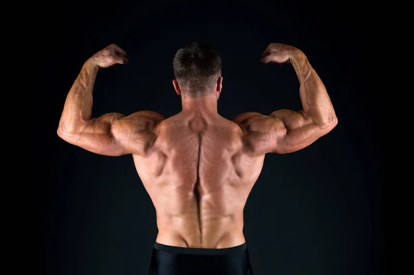 Deportista del año. Vista trasera del deportista sobre fondo negro. Fuerte deportista flexionando los músculos del brazo tríceps bíceps. Deportista o culturista mostrando espalda muscular —  Fotos de Stock