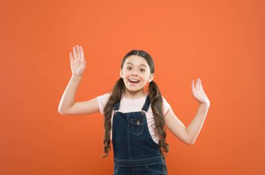 Mutlu ve heyecanlı görünüyorsun. Turuncu arka planda sevimli gülümseme ile Mutlu küçük kız. Neşeli küçük çocuk mutlu moda bakmak ile gülümseyerek. Sevimli çocuk mutlu çocukluk zevk
