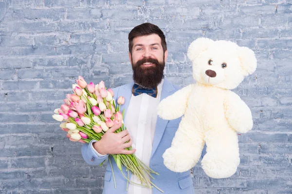 Macho getting ready romantic date. Waiting for darling. Man well groomed wear tuxedo bow tie hold flowers tulips bouquet and big teddy bear toy. Invite her dating. Romantic gift. Romantic man — Stock Photo, Image