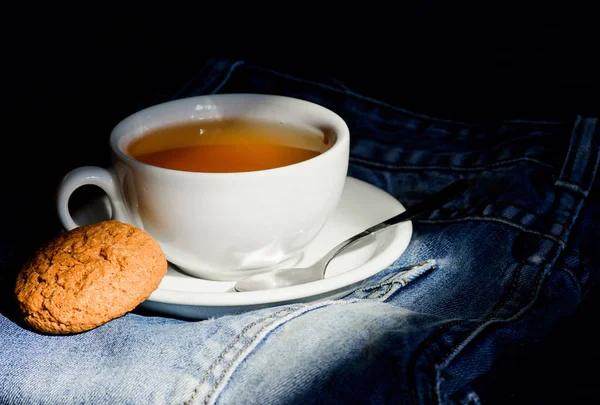 Healthy habits. Tea time concept. Cup mug hot water and bag of tea. Mug filled boiling water and tea bag on blue jeans background. Herbal green or black whole leaf. Process tea brewing in ceramic mug