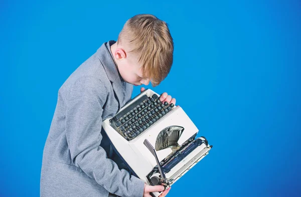 Retro and vintage. Yard sale. Retrospective study. Boy hold retro typewriter on blue background. What to do with this thing. Out of date. I need modern gadget instead this retro. Outdated gadget