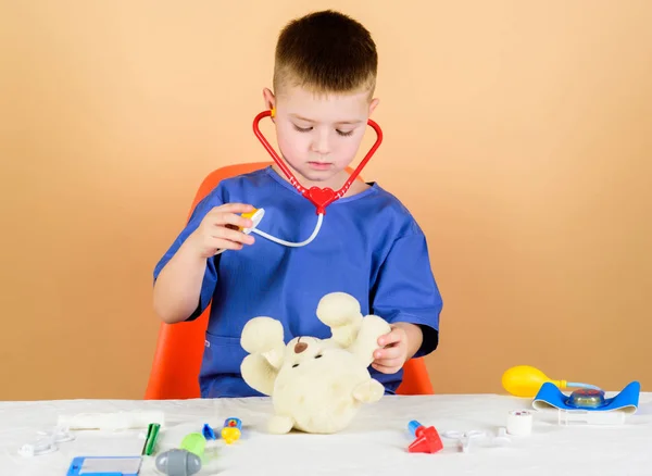 Medical education. Boy cute child future doctor career. Health care. Kid little doctor busy sit table with medical tools. Medical examination. Medicine concept. Medical procedures for teddy bear — Stock Photo, Image