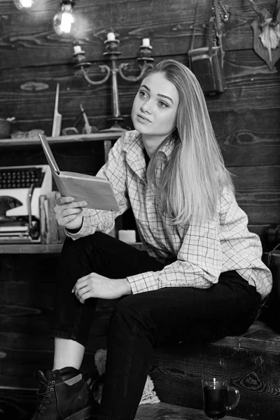 Kız öğrenci çalışma kitabı içinde hakem ev ile. Çalışma kavramı. Bayan kareli giysiler içinde sakin yüzünde sevimli ve rahat görünüyor. Ahşap vintage iç kitap ile gündelik kıyafeti kız oturur