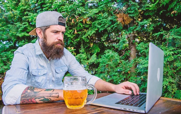 Taking the online world and beer mug with him. Computer keyboard operator. Computer user drinking beer in outdoor cafe. Bearded man working on laptop computer. Computer and information technology — Stock Photo, Image