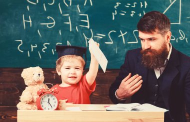 Küçük çocuk onun defterini boya ile gösterir. Baba, evde ile tek tek çocuk mutlu çalışmalar. Bireysel eğitim kavramı. Öğretmen ve öğrenci kolej, kara tahta arka plan içinde