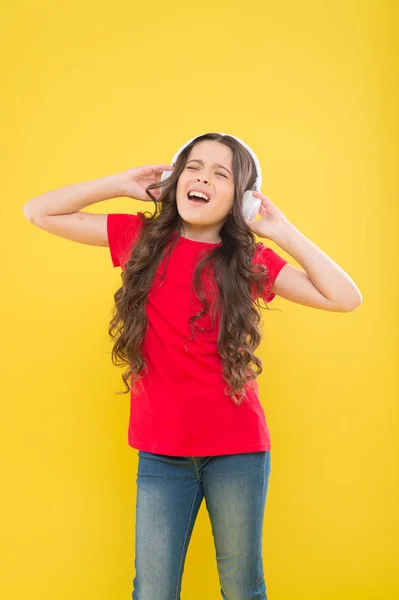 Dulce canción para empezar la música. Linda cantante de canciones sobre fondo amarillo. Niña cantando canciones tocando en auriculares. Adorable niño pequeño haciendo vocal en la canción — Foto de Stock