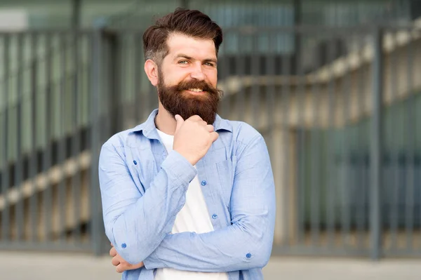 Pensive hipster thinking pleasant thoughts. Man bearded hipster urban background. Regular walk in city center. Confident hipster stand in street alone. Right here and now. What is on his mind