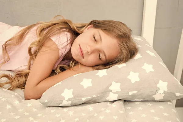 Conseils pour dormir sainement. Fille dormir sur un petit oreiller fond de linge de lit. Enfant longs cheveux bouclés s'endorment oreiller de près. Choisissez un oreiller approprié pour vous détendre. Oreiller mignon et linge de lit pour chambre à coucher enfantine — Photo