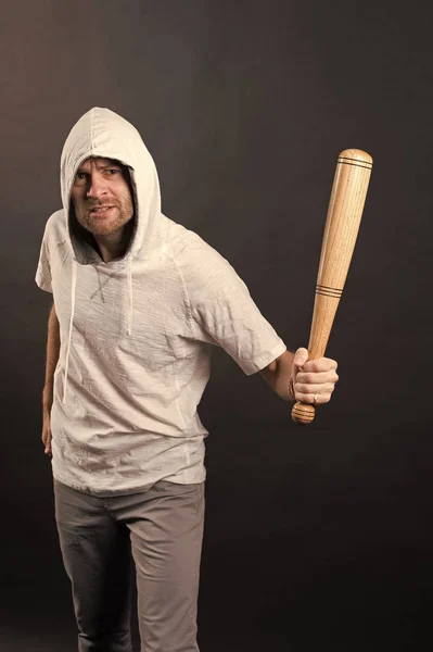 Bearded man hold baseball bat. Hooligan wear hood in hoodie tshirt. Gangster guy threaten with bat weapon. Aggression or anger and violence concept — Stock Photo, Image