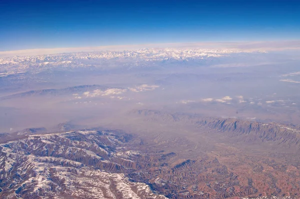 Jordens yta med snötäckta berg på blå himmel, Flygfoto. Miljöskydd och ekologi. Bergslandskap. Upptäckter och äventyr. Jorden varje dag — Stockfoto