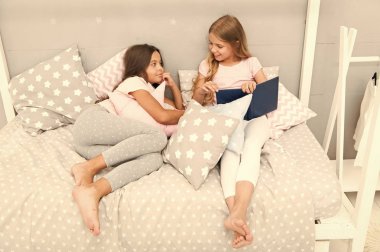 Çocuklar yatmaya hazırlanın. Hoş zaman konforlu yatak odası. Uzun saçlı hoş pijamalı kızlar rahatlar, kitap okurlar. Kitabın mutlu sonundan memnun. En sevdikleri kitap. Kız kardeşler birlikte yatar, kitap okurlar.