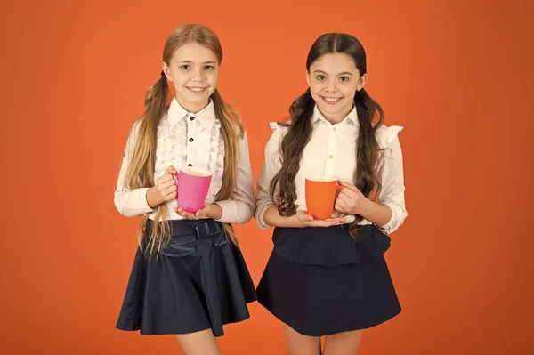 Um bom dia para ti. Crianças pequenas bebendo chá ou café da manhã. Estudantes bonitos segurando xícaras de chá. Crianças em idade escolar tomando café da manhã. Meninas pequenas desfrutando de seu café da manhã escolar — Fotografia de Stock