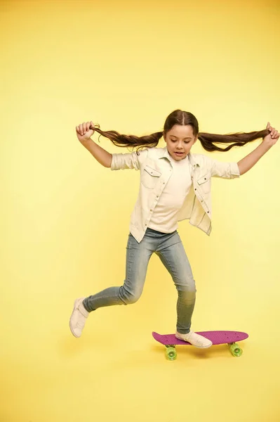 Conceito de lazer ativo. O miúdo a divertir-se com o Penny Board. Criança sorridente face stand no skate. Penny board bonito skate colorido para meninas. Vamos cavalgar. Menina passeio penny board amarelo fundo — Fotografia de Stock