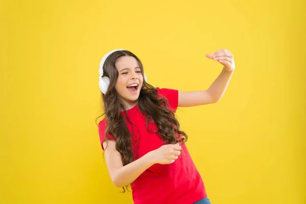 When the soul is singing. Adorable small child singing on yellow background. Cute little girl listening to music in earphones and singing song. Musician enjoying solo singing — Stock Photo, Image