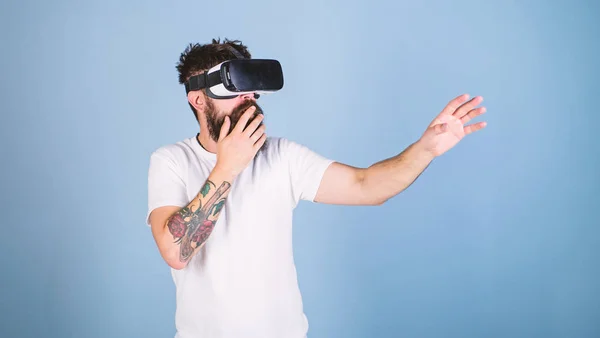 Hipster sul viso scioccato esplorare la realtà virtuale con gadget moderno. Il ragazzo con display a testa interagisce nella realtà virtuale. Uomo con barba in VR, sfondo azzurro. VR concetto gadget — Foto Stock