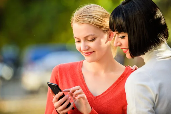 Navegar por Internet. Comunicarse en línea. Las chicas se comunican mirando el teléfono. Compra en línea. Dos mujeres con smartphone que se comunican al aire libre. Concepto de redes sociales. Enlace compartido. Tecnología moderna —  Fotos de Stock