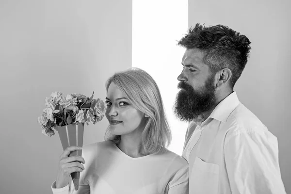 Kvinna njuta av doften bukett blommor. Par i kärlek lycklig fira årsdagen. Mannen med skägg hand tar om flickvän lycka. Lady gillar blomma man begåvad henne. Blommor leverans koncept — Stockfoto