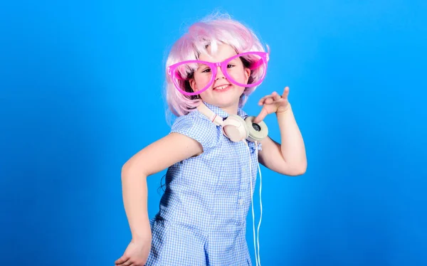 Auriculares de niña pequeña peluca rosa bailando. Niño usando la tecnología para divertirse. Auriculares modernos. Danza de movimiento de energía. Inspirado en la música. Un niño escuchando música. Lindo niño con auriculares fondo azul — Foto de Stock