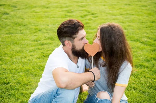 Secret kiss. Man bearded hipster and pretty woman in love. Summer vacation. Happy together. Couple in love cheerful youth booth props. Emotional couple radiating happiness. Couple relaxing green lawn