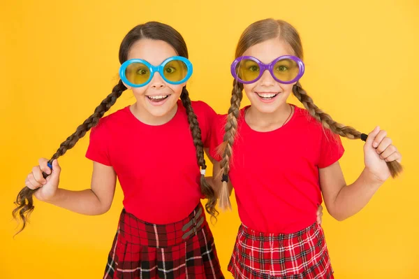 Accessoire d'été. Filles sœurs mignonnes tenues similaires portent des lunettes de soleil colorées pour la saison estivale. Enfants amis à la mode posant dans des lunettes de soleil sur fond jaune. Tendance mode estivale. Plaisir d'été — Photo