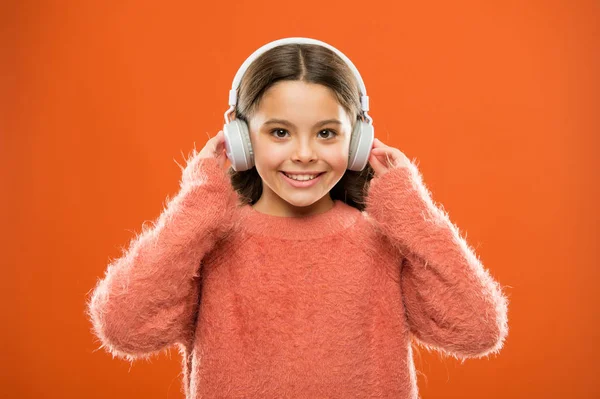 Fones de ouvido estéreo de som perfeito. Menina bonito criança usar fones de ouvido ouvir música. Miúdo ouvir música fundo laranja. Música recomendada com base no interesse inicial. Música produz prazer — Fotografia de Stock