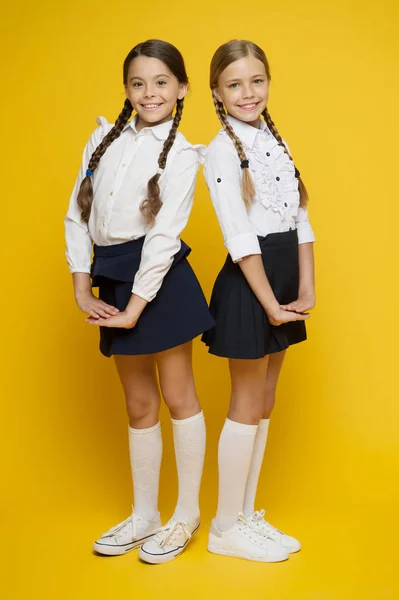 Prémio dos melhores alunos. Fazendo tudo certo. Excelentes pupilas. Meninas roupa uniforme perfeito no fundo amarelo. Segundo as regras da escola. Colegas de turma alunos arrumados. Programa educacional para crianças talentosas — Fotografia de Stock