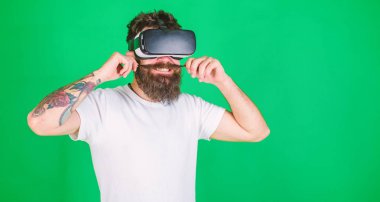 Hippi kurnaz ifadeyle Vr modern becerikli alet ile keşfetmek. VR gadget kavramı. Vr bardaklarda sakallı bıyıklı, yeşil arka plan katlanmış. Adam kafa monte ekran ile etkileşim içinde Vr