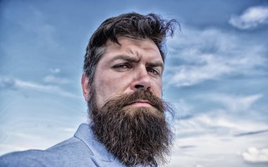 Adam sakallı hippi bıyık mavi gökyüzü arka plan ile. Büyüyen ve bıyık sürdürmek için uzman ipuçları. Hipster ciddi yakışıklı çekici sakallı adam uzun. Nihai bıyık damat Kılavuzu