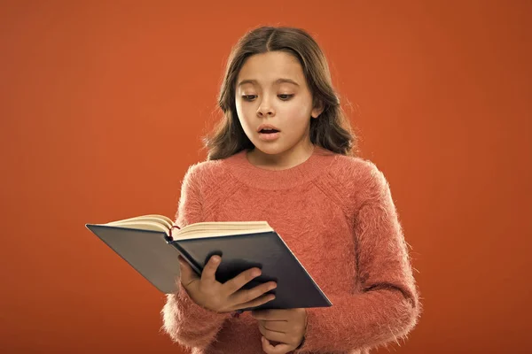 Reading practice for kids. Childrens literature. Girl hold book read story over orange background. Child enjoy reading book. Book store concept. Wonderful free childrens books available to read — Stock Photo, Image