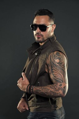Moda stil ve eğilim. Pazı ve triceps dövmeli adam. Tıraşsız yüzündeki sakallı dövme modeli. Güçlü silah dövme sakallı adam. Moda maço trendy güneş gözlüğü