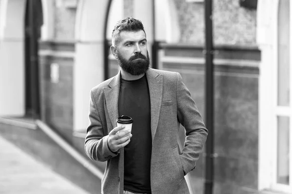 Man bearded hipster drinking coffee paper cup. One more sip of coffee. Drinking coffee on the go. Businessman lumbersexual appearance enjoy coffee break out of business center. Relax and recharge