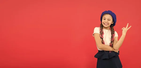 Sólo me divierto. Vacaciones de verano. Niña pequeña linda chica de moda posando con trenzas largas y sombrero fondo rojo. Niño niña pequeña feliz bebé sonriente. Feliz infancia. Publicidad niño feliz espacio de copia — Foto de Stock