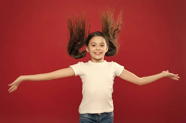 Enfant sourire visage mignon vivre une vie heureuse insouciante. Profitez de chaque instant. Jeune et libre. Joyeux enfant fille aux cheveux longs sur fond rouge. Bonheur et joie. Des émotions positives. Garde et éducation des enfants — Photo