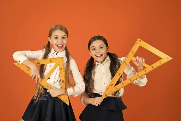 Sin geometría la vida no tiene sentido. Las niñas han vuelto a la escuela. Colegialas lindas sosteniendo triángulos para la lección. Niños en edad escolar con instrumentos de medida. Niñas listas para la lección de geometría —  Fotos de Stock