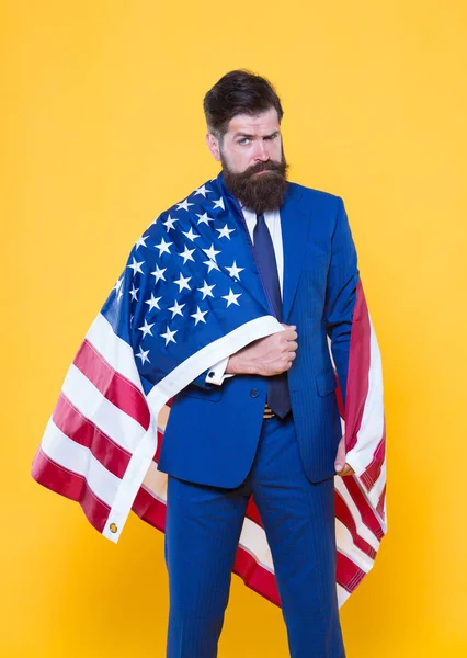 La bandera inspira sentimientos de orgullo y seguridad. Un hombre de negocios seguro llevando bandera americana con orgullo. Hombre barbudo en ropa formal sintiendo orgullo nacional en el día de la independencia. Orgullo y dignidad — Foto de Stock