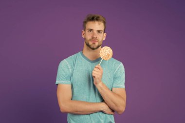 Lolipop eğlencesi. Adam kocaman renkli lolipop yiyor. Tüylü adam lolipopu seviyor. Yemek konseptini aldatmak. Şeker sağlığa zararlıdır. Adamın elinde lolipop şeker menekşesi var. Çocukluk tadı