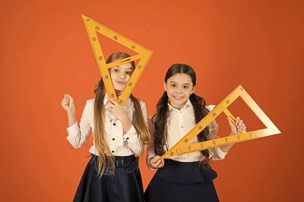 Volviendo a las raíces cuadradas. Niñas listas para la lección de geometría. Las niñas han vuelto a la escuela. Niños en edad escolar con instrumentos de medida. Lindas colegialas sosteniendo triángulos para la lección —  Fotos de Stock