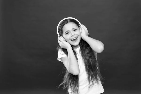 Cantando con una melodía. Niña escuchando música. Pequeño niño que usa la tecnología para el ocio o la educación. Niña pequeña con auriculares estéreo. Lindo ventilador de música con auriculares inalámbricos — Foto de Stock