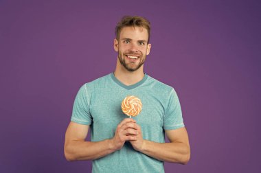 Şeker sağlık için zararlı. Adam lolipop şeker menekşe arka plan tutun. Adam yakışıklı maço büyük renkli tatlı lolipop yemek. Çocukluk tadına. Kıl adamla Lolipop sever. Yemek kavram hile