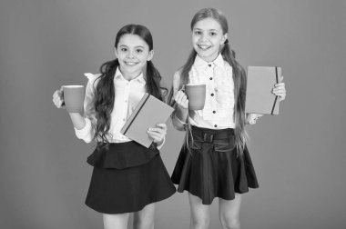 Gününüze enerji. Bardak ve kitap tutan şirin kız öğrenciler. Küçük çocuklar sabah çay veya süt içme. Okul çocukları sabah odaya sahip. Küçük kızlar onların okul kahvaltı keyfi