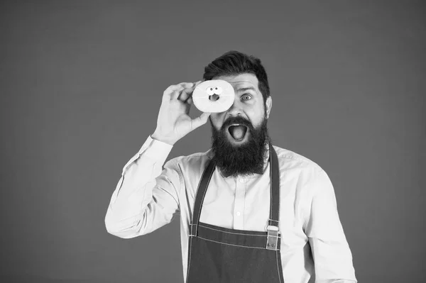 Tu es ce que tu manges. boulanger tenir beignet. Un drôle de hipster. Un homme barbu cuisinier. Chef au café. Régime alimentaire et des aliments sains. L'homme barbu mange du beignet. Calorie. Ressens la faim. Chef barbu. Homme barbu dans le tablier — Photo