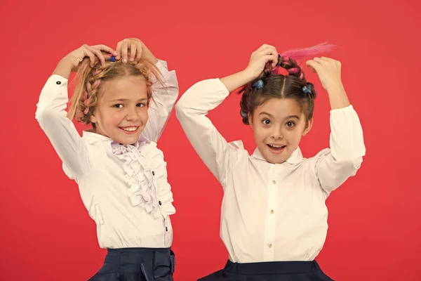 Mantenha o cabelo trançado para olhar arrumado. Os alunos de crianças brincam com o cabelo trançado longo. Salão de cabeleireiro. Penteados que se adaptam ao estilo escolar formal. Penteado apropriado. Meninas tranças longas fundo vermelho — Fotografia de Stock