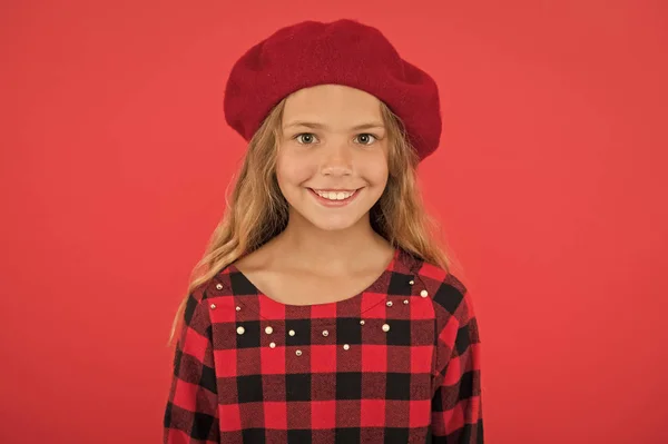 Miúda menina bonito sorriso rosto posando em chapéu fundo vermelho. Acessório de boina na moda de mulher. Como usar boina francesa. Inspiração de estilo boina. Como usar boina como menina da moda — Fotografia de Stock