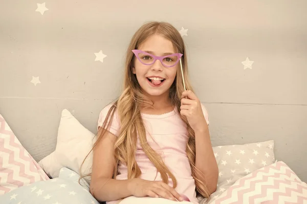 Slumber party foto stand props. Kid meisje vrolijk poseren met roze bril partij kenmerk. Voorbereiden foto stand rekwisieten hand gemaakt of kopen voor de partij. Kijk naar de wereld door middel van roze gekleurde glazen — Stockfoto