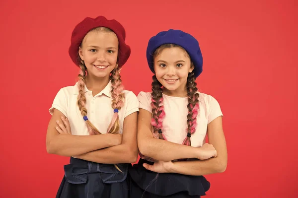 Stylish and confident. Cute girls having the same hairstyle. French style girls. Small children with long hair plaits. Fashion girls with tied hair into braids. Little kids wearing french berets — Stock Photo, Image